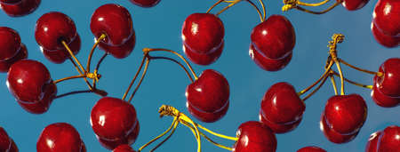 A scattering of bright burgundy berries of cherries on the mirror, which reflects the blue sky....