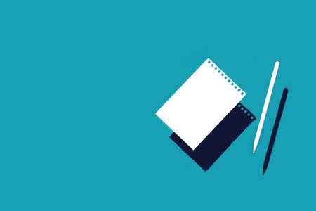 A clean white sheet torn from a spiral pad and a pencil. On a blue background with shadowsの写真素材