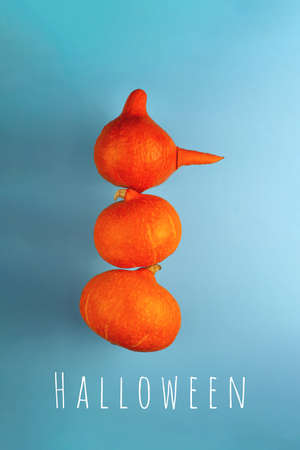 A snowman with a carrot nose of three orange pumpkins on a blue background. Halloween concept.の写真素材