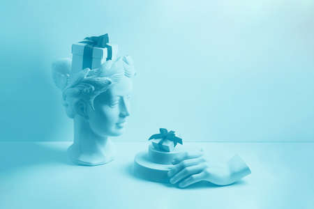 Composition with gypsum bust and hand. A box with a red ribbon in head and on the podium. Gift...
