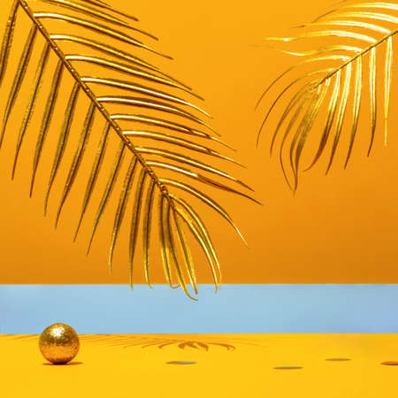 Golden candles with the new year 2021 on the marble arch, palm leaves, confetti on a yellow background with the horizon. Festive trend still life.の写真素材