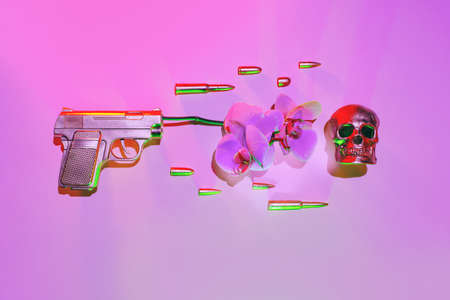 The golden gun shoots an orchid flower, next to fly bullets on a pink background, the concept against the war.の写真素材
