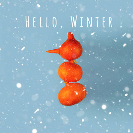 A snowman with a carrot nose of three orange pumpkins on a blue background. Halloween conceptの写真素材