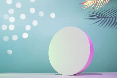 Round podium mockup in horizontal composition with golden palm leaves on a blue background with neon illumination, place for your textの写真素材