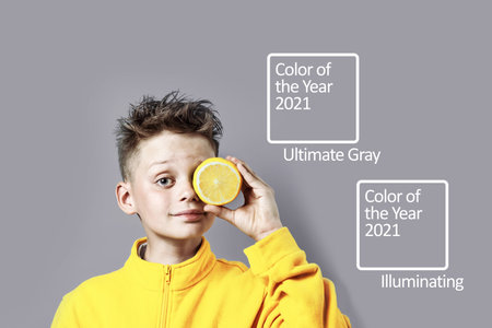 a boy in a bright yellow jacket with a lemon in his hand on a blue backgroundの写真素材
