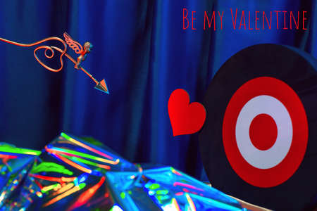 Small golden cupid marks his target with an arrow at the heart, valentines day concept.の写真素材