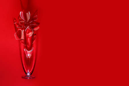 A wine glass shattered into small fragments, as a symbol of a quarrel, an accident, a rupture, on a bright red backgroundの写真素材