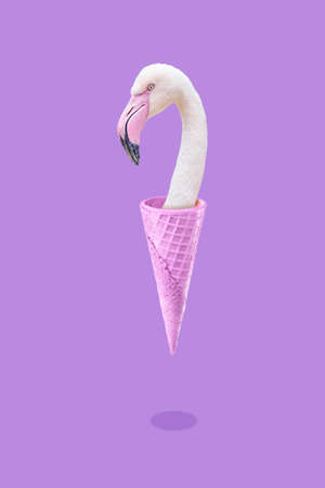 Pink flamingo in an ice cream waffle cone, a symbol of summer and vacation in the tropics by the sea, a trendy collage concept on a purple background.の写真素材