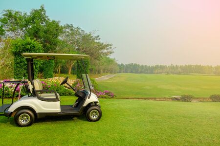 Golf cart car in fairway of golf course with fresh green grass field and cloud sky and treeの写真素材