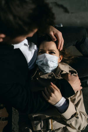 A girl in a medical mask who became ill with coronavirus lies on her husbands lapの写真素材