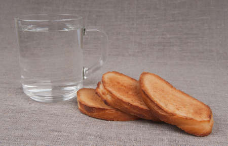 Grain crackers and a cup of pure water on a linen backgroundの写真素材