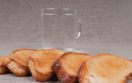 Grain crackers and a cup of pure water on a linen backgroundの写真素材