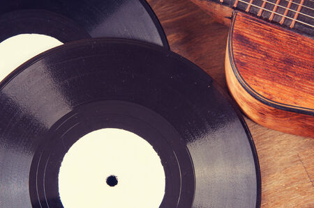 Vintage acoustic guitar and vinyl record on a wooden background