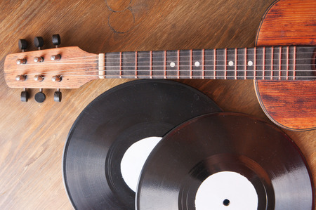 Vintage acoustic guitar and vinyl record on a wooden 