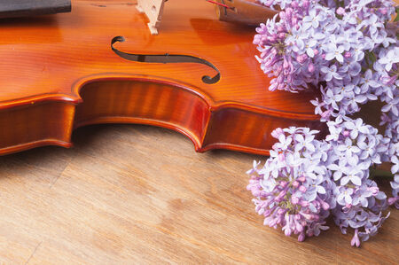 Violin and a bouquet of lilacs on a wooden tableの写真素材