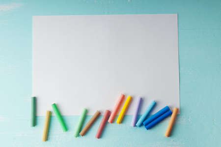 Blank sheet of paper and pastels on turquoise wooden surfaceの写真素材