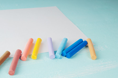 Blank sheet of paper and pastels on turquoise wooden surfaceの写真素材