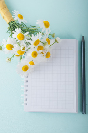 Blank notebook, a pencil and a bouquet of daisiesの写真素材