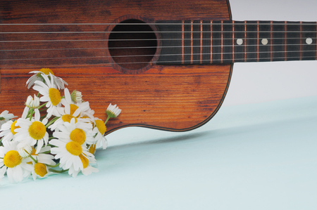 Little guitar and a bouquet of daisies on the azure surfaceの写真素材
