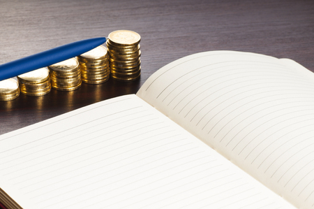rows of gold stack coins, pen and noteの写真素材