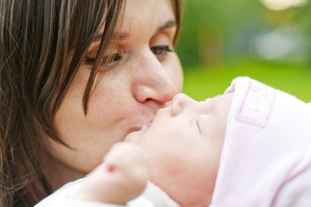 Young mother kissing her newborn babyの写真素材