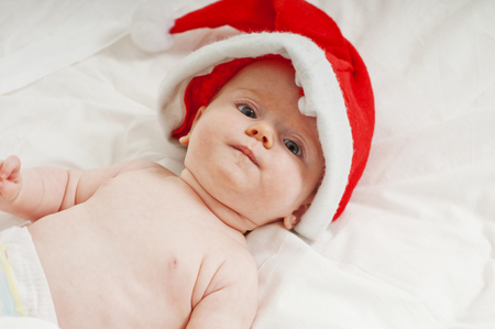 Charming newborn baby dressed as Santa Claus on the bedの写真素材