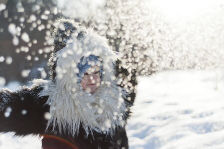 Little girl in fox fur coat looking at the falling snow in winter park. Snowfall