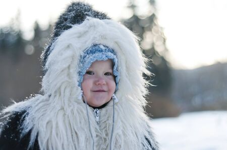 Little girl in a fur coat walks in the winter parkの写真素材