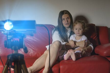 Mother and daughter watching a movie at home with the projectorの写真素材