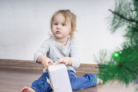 Girl opens Christmas present at homeの写真素材