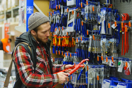 EKATERINBURG, RUSSIA - JANUARY, 8, 2018: A young man chooses iron straight pipe adjustable wrench...