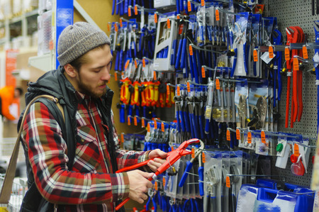 EKATERINBURG, RUSSIA - JANUARY, 8, 2018: A young man chooses iron straight pipe adjustable wrench plumbing water gas in the hardware storeのeditorial素材