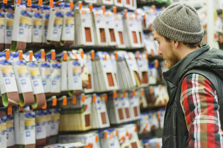 A young man chooses highly rigid grinding paper in the hardware storeの写真素材