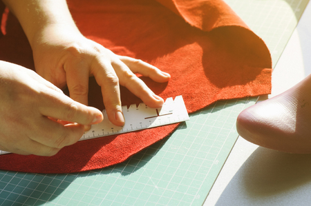 Hands of the master. Marking and slicing red leather for making bags, purses or shoes.の写真素材