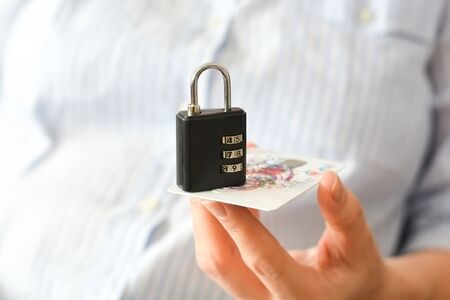 Business woman holding a combination lock and a credit or debit card suggesting payment securityの写真素材