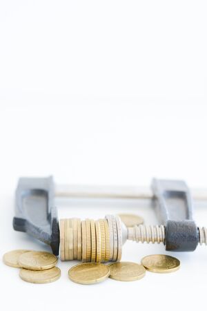 Economy pressure concept with stack of coins in a crampの写真素材
