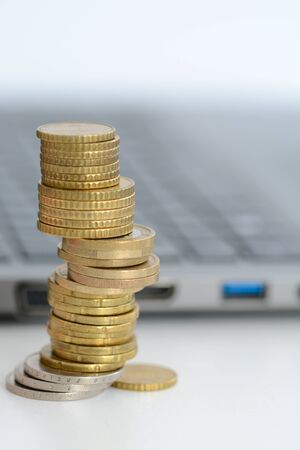 Stack or pile of coins and a laptop keyboardの写真素材