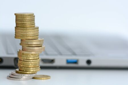 Stack or pile of coins and a laptop keyboardの写真素材