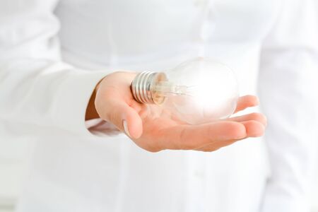 Businesswoman holding in hand a light bulbの写真素材