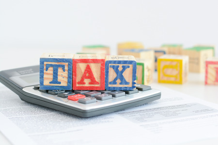 Taxation concept with wooden cubes and pocket calculatorの写真素材