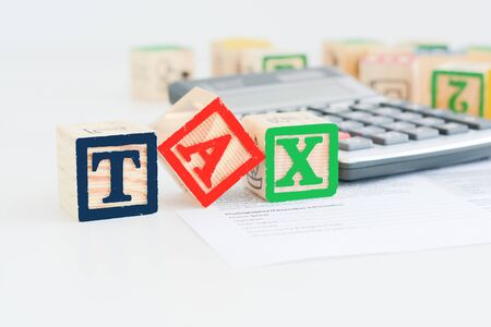 Taxation concept with wooden cubes and pocket calculatorの写真素材