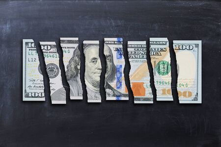 US Dollar bill cut in pieces suggesting weak economyの写真素材