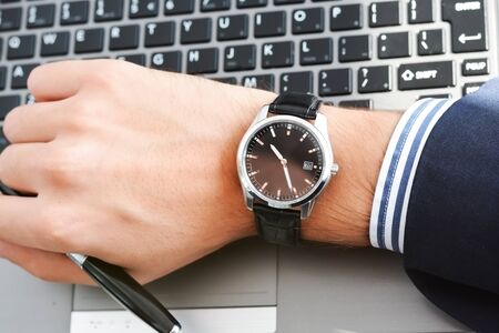 Businessman hand looking at his watch suggesting being out of timeの写真素材