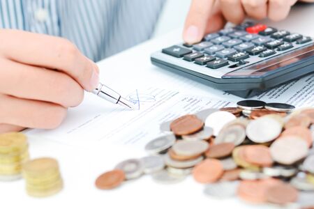 Tax calculation or new loan agreement with hand calculator and coinsの写真素材