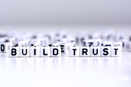 Build trust process concept with tiled letters on white background