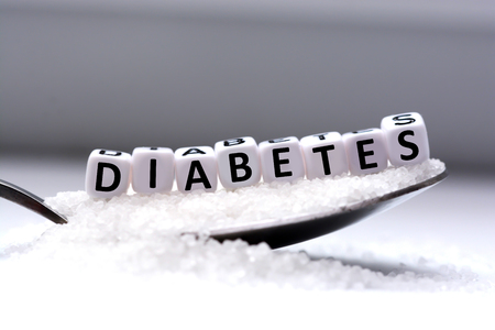 Plastic letter beads spelling âdiabetesâ in a spoon full of sugarの写真素材