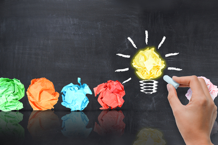 Bright idea concept with light bulb shaped crumpled paper on blackboardの写真素材