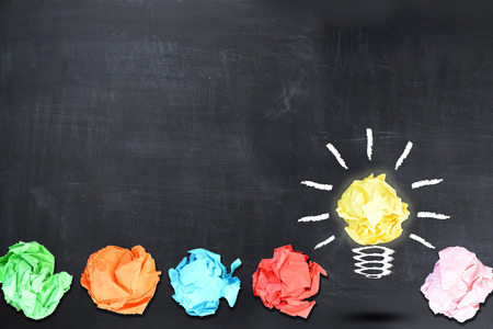 Bright idea concept with light bulb shaped crumpled paper on blackboardの写真素材