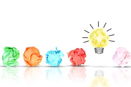 Breakthrough concept with multiple colorful crumpled pieces of paper around a yellow bright light bulb shaped paper on white backgroundの写真素材