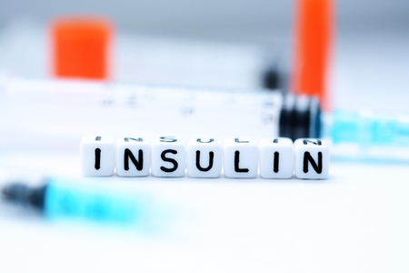The word insulin spelled with plastic letter beads next to a syringeの写真素材